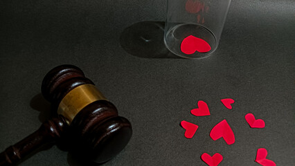 A symbolic image showing a judge’s gavel, and red heart shapes, representing the balance between love, money, and justice in relationships, divorce, or emotional decisions.
