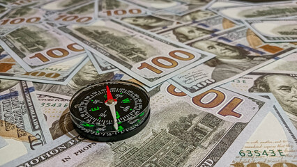 A compass placed on a spread of hundred-dollar bills, symbolizing time, wealth, and guidance in financial decisions and investment strategies.