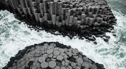 Dramatic aerial view of hexagonal basalt columns forming natural sea stacks battered by ocean waves