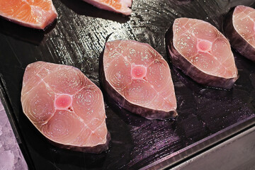 Fresh, prepared king mackerel steak displayed on a vendor's tray at a fish market. For themes usage of healthy food, seafood, gourmet cooking, ketogenic diet and restaurant menus. Real fish meat