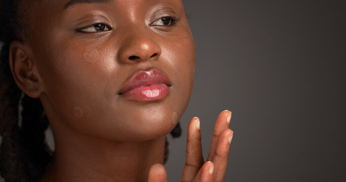 Acne patch, beauty and lip gloss with black woman on studio space for cosmetics or dermatology. Inspection, skincare and treatment with African model isolated on gray background to remove pimple