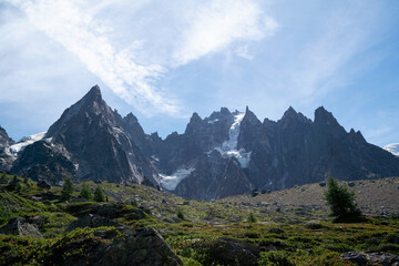 Dramatic spire-shaped mountain range rising over low shrubs and scattered boulders