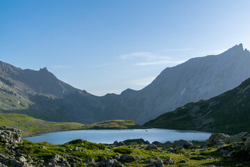 Obraz premium Alpine lake and fresh green grass with French mountains in the background