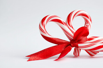 Fototapeta premium Candy cane tied with red ribbon and bow, white background 