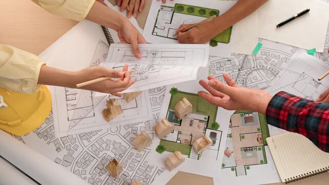 Architect and safety engineer discussion about building construction use blueprint on table with architectural document, measurement tool and wooden block scatter around at modern office. Delineation.