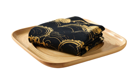 Folded black cloth with gold wave pattern on square wooden plate against black background