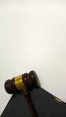 A wooden judge's gavel with a golden band placed on a white surface beside a black leather notebook,symbolizing justice, law, and legal decision-making.