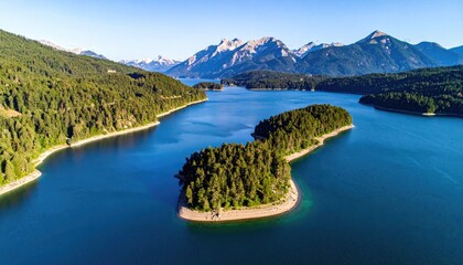 Vast Blue Lake Surrounded by Lush Green Forests and Majestic Mountains Under a Clear Blue Sky