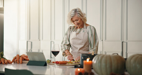 Mature woman, tablet or cutting on kitchen counter, prepare ingredients or video tutorial for...