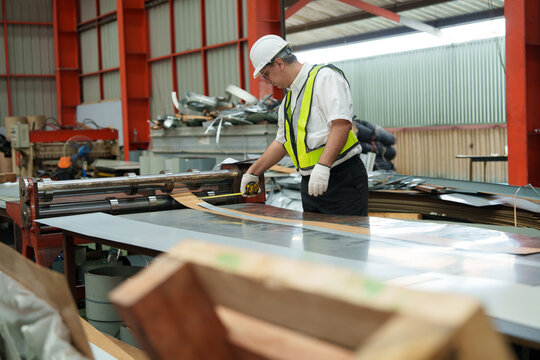 A supervisor is inspecting a component production line in a sheet metal and metal roofing manufacturing plant.