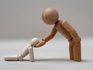 Wooden mannequin reaching hand to help fallen figure, symbolizing kindness, trust, and emotional assistance in human compassion and connection.
