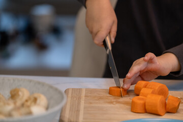 Child cutting carrot during safe cooking lesson at home