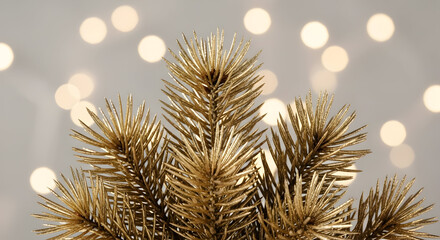 Golden Christmas Tree Branch Against Blurred Lights Background for Festive Season