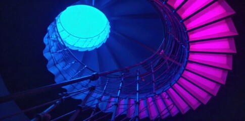 Futuristic glowing spiral staircase, sci fi design, neon lights, vibrant colors, technological innovation, advanced engineering. A futuristic spiral staircase with a sleek, metallic structure emitting