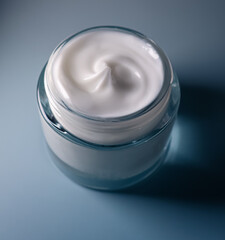 White cosmetic cream in a glass jar, showing texture and promoting skincare, beauty and hydration products