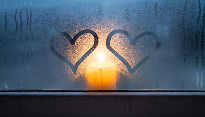 Candle behind steamy window with two drawn hearts.