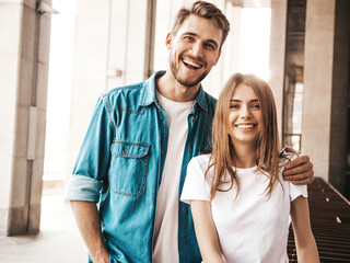 Naklejka premium Portrait of smiling beautiful female and her handsome boyfriend. Woman in casual summer jeans clothes. Happy cheerful family. Female having fun on the street background