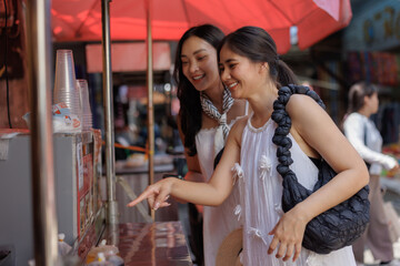 Smiling women pointing at street food stall in market