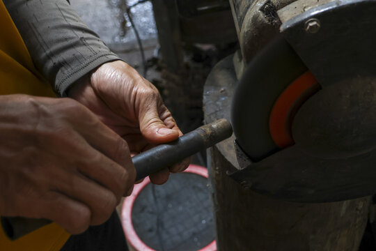 Close up of worker hand grinding metal tool on sharpening machine in workshop. focused craftsman using industrial equipment for precision work and maintenance - Powered by Adobe