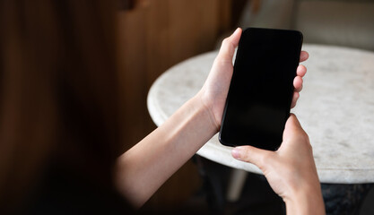 Closeup of woman holding smartphone with blank screen, perfect for mobile app mockup, technology, digital communication, and online lifestyle concept.