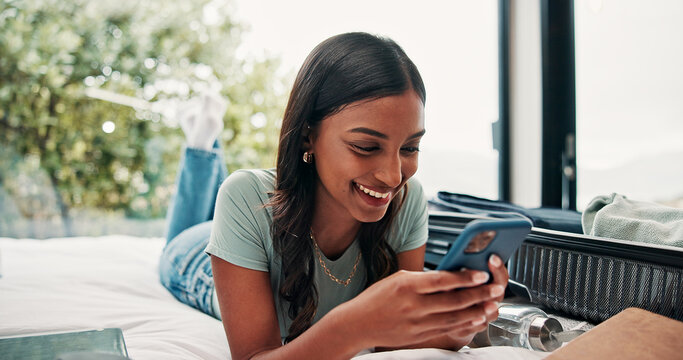 Happy woman, travel and unpacking with phone in bed for vacation, holiday or accomodation in hotel. Female person, traveler or tourist with smile, mobile smartphone or suitcase for check in app - Powered by Adobe