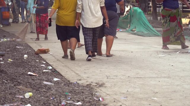 People walking on street in morning 2 ladies They are cleaning up garbage on the road. USP