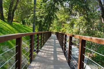 A wooden bridge with a fence along the river. Park area.  Terrenkur.