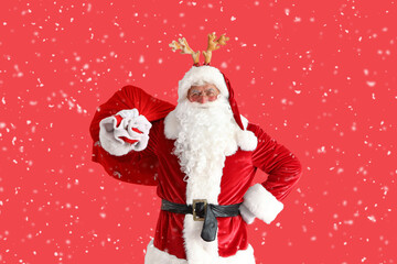 Santa Claus in deer horns with Christmas bag on red background