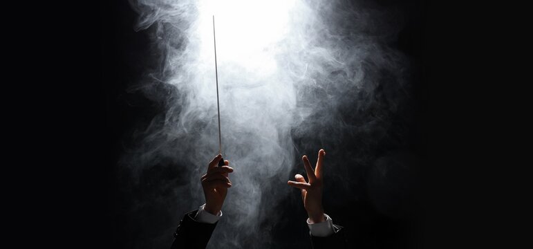 Hands of conductor on dark background