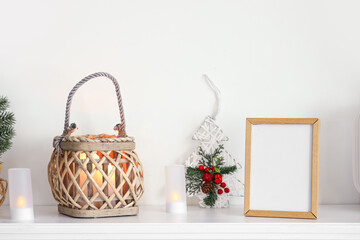 Glowing lantern, Christmas decor and blank frame on mantelpiece in festive living room, closeup