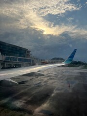 Airplane Wing View During Early Morning Takeoff Under Cloudy Sky. Scenic view from inside an airplane showing the wing and runway during early morning takeoff under dramatic cloudy skies
