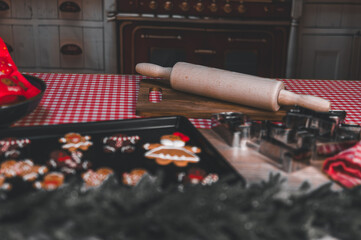 Christmas baking scene with gingerbread cookies, rolling pin, cookie cutters, and festive table setting. Cozy holiday atmosphere in a warm kitchen.