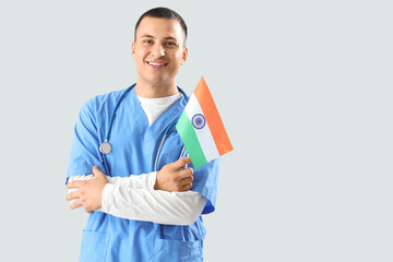 Male doctor with flag of India on grey background. National Doctor's Day celebration