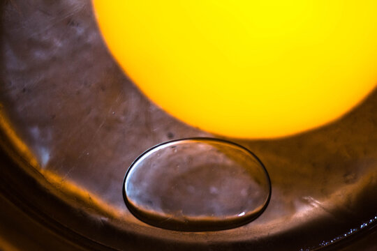 water droplet on reflective surface with yellow bokeh