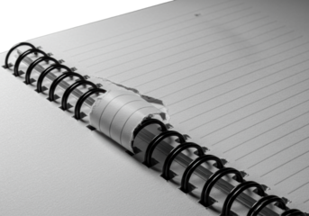 Macro, ultra close-up, low angle view of an open spiral-bound notebook with a dramatically torn white ruled page, fibrous edges, and black metal binding on gray. Precise study of stationery textures