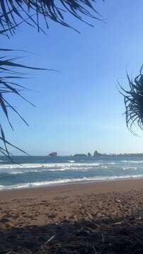 The sea in Jember, East Java. Indonesia. Watu Ulo beach with dark sand, mountains and coral rocks towering above the beach. The raging blue Indian ocean on a sunny day. 4К