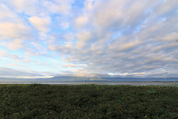 Background of bright white cloudy sky in the morning with mountains and river.