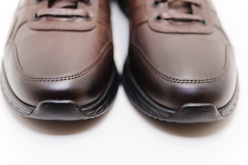 Brown leather sneakers with black soles in focus
