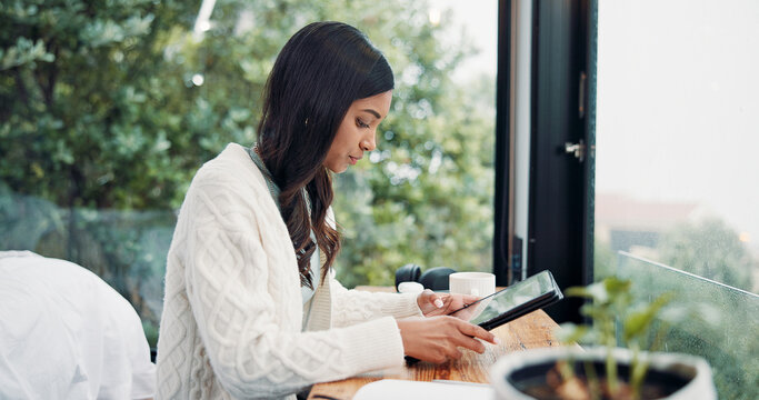 Reading, remote work and tablet with woman in home for online planning or research at window. App, development and scrolling with freelance employee at desk in apartment for small business startup