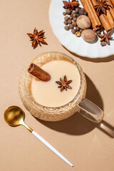 Traditional Indian masala chai tea with milk and spices in a cup on a beige background
