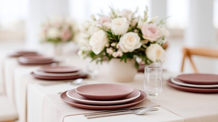 Elegant dining table set with pink plates and cutlery, adorned with a beautiful floral centerpiece, creating a sophisticated atmosphere for special occasions and gatherings