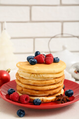 Plate of sweet pancakes with berries and Christmas ball on white table