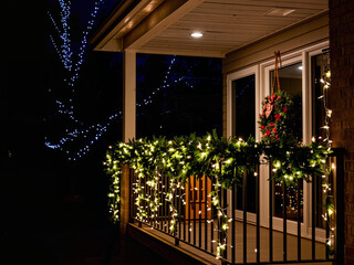 Christmas night balcony with fairy lights Cozy porch decorated with Christmas lights and wreath at night  