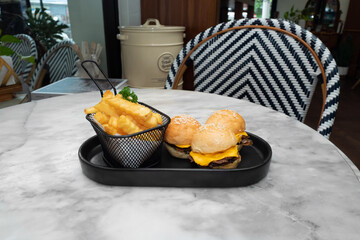 Delicious mini burgers and french fries served on a table