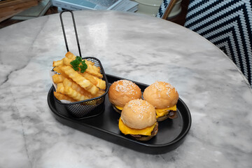 A tempting close-up of mini burgers and fries on a stylish tray, ready to savor. The burger is a tasty and the fries are crispy and golden.