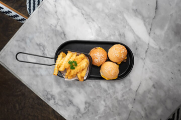 Delicious Mini Burgers with Golden Fries on a Marble Table. The presentation of the food is both appetizing and visually appealing. 