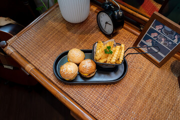 A delicious meal of sliders and fries on a wooden table. The sliders are small burgers, and the fries are crispy and golden.