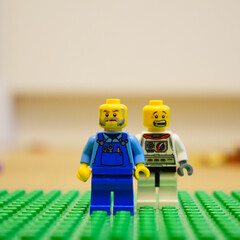 Fototapeta premium Lego minifigures of a farmer and an astronaut standing together on a green baseplate