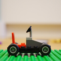 Fototapeta premium A small toy car made of colorful building blocks on a green base