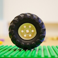 Fototapeta premium Close-up of a black Lego wheel on a green baseplate, a toy concept